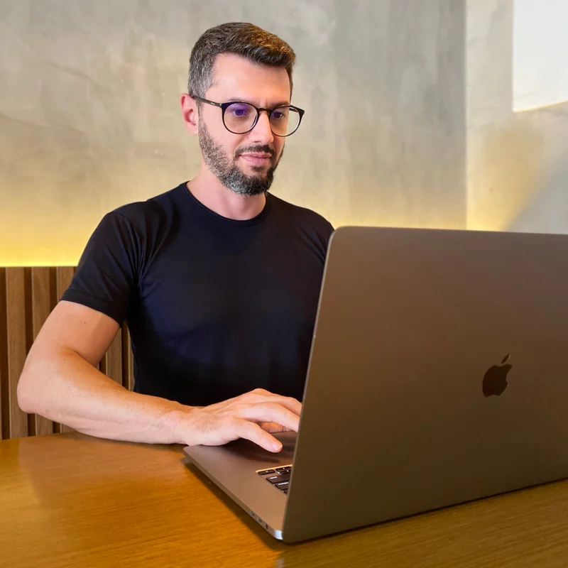 Professor Tiago Segato usando seu computador em um ambiente aconchegante